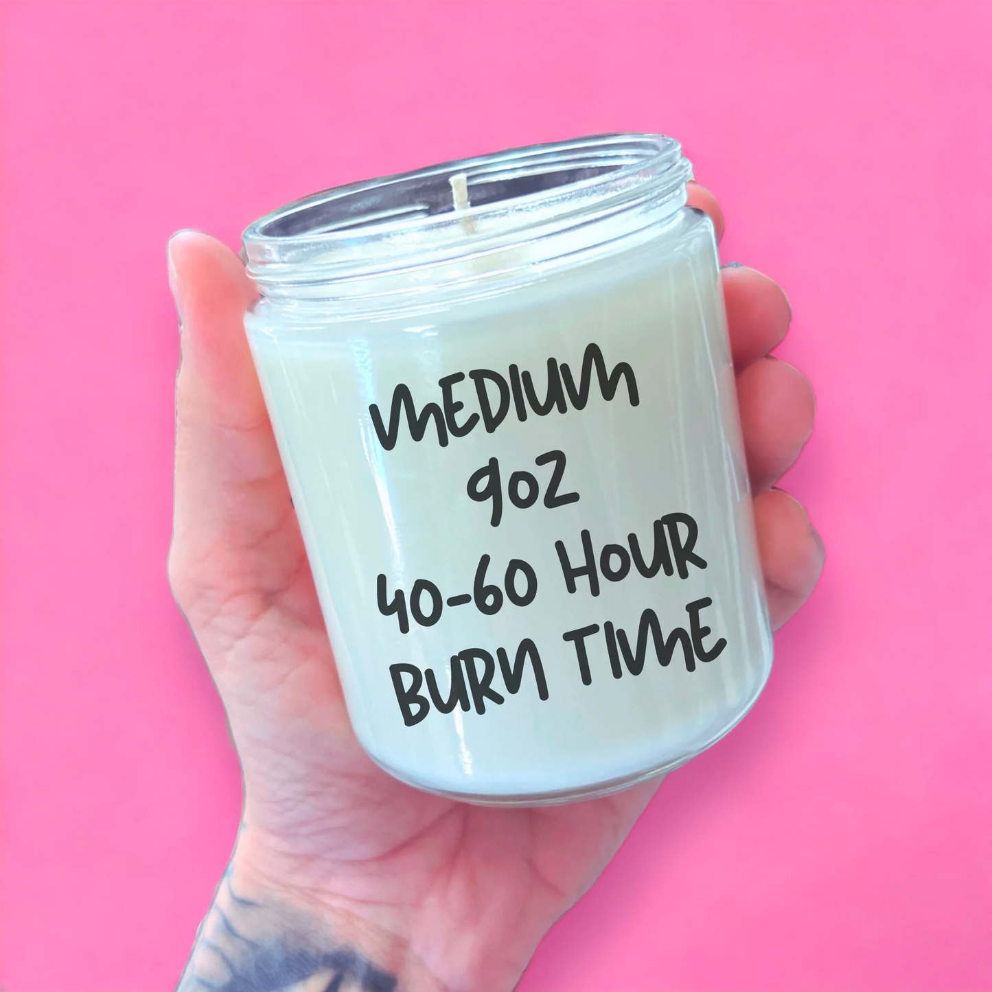 a person holding a candle that says medium goz 40 - 60 hour burn time